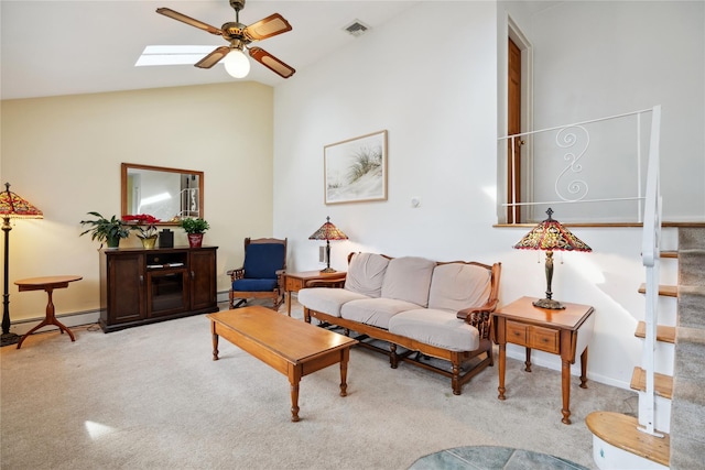 living area with light carpet, vaulted ceiling with skylight, visible vents, ceiling fan, and stairway