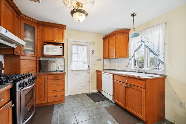 kitchen featuring a healthy amount of sunlight, white appliances, glass insert cabinets, and brown cabinetry