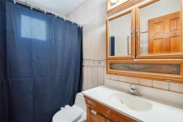 full bath with toilet, wallpapered walls, curtained shower, and vanity