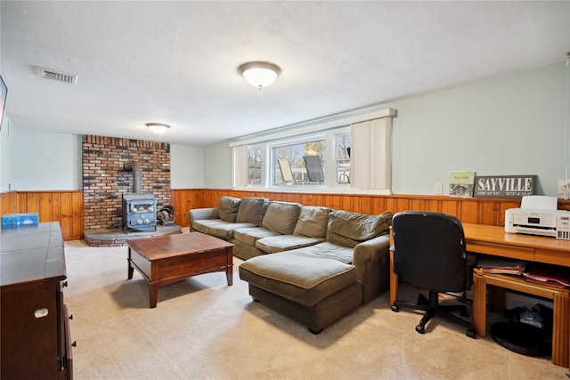 living area with wainscoting, visible vents, light carpet, and a textured ceiling