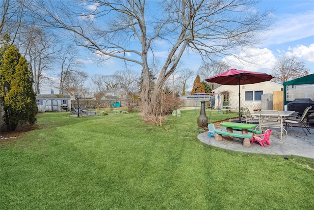 view of yard with a fenced backyard, a patio, an outdoor structure, and a storage unit