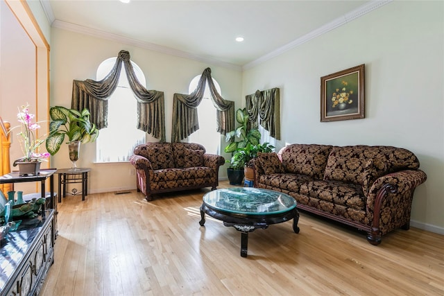 living room with ornamental molding, visible vents, light wood-style flooring, and baseboards