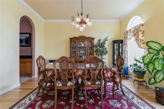 dining space with ornamental molding, arched walkways, and wood finished floors