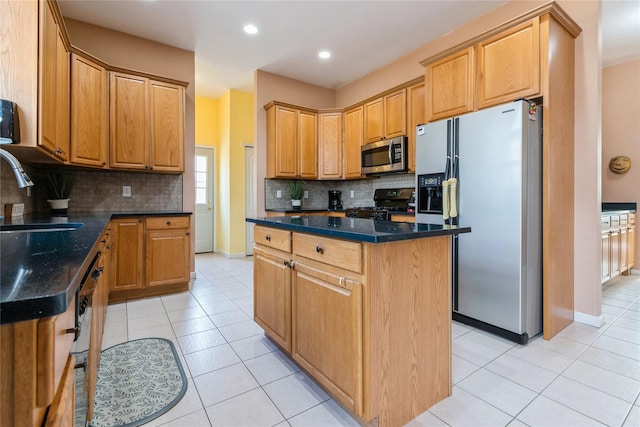 kitchen featuring light tile patterned floors, a sink, appliances with stainless steel finishes, a center island, and dark stone counters