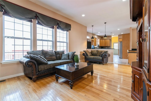 living area featuring light wood-style flooring, baseboards, and recessed lighting