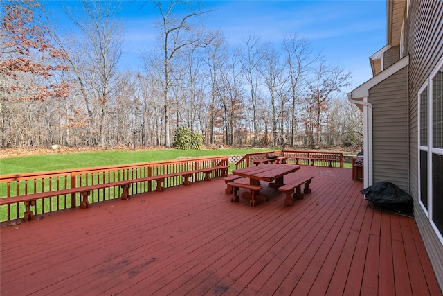 wooden terrace featuring outdoor dining area and a lawn