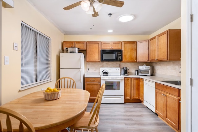 kitchen featuring light wood finished floors, light countertops, white appliances, and backsplash