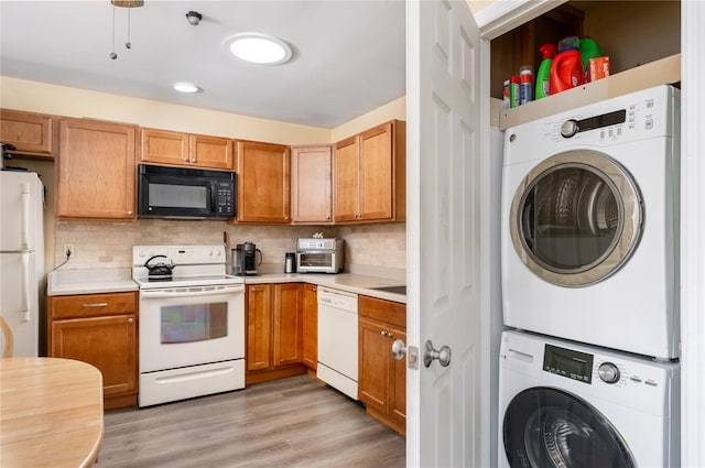 kitchen with white appliances, stacked washer / drying machine, light countertops, light wood-type flooring, and decorative backsplash