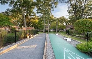 view of property's community featuring fence and shuffleboard