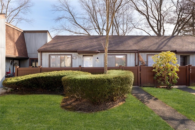 view of front of house featuring fence, a front lawn, and roof with shingles