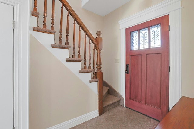 foyer entrance featuring light carpet, stairs, and baseboards