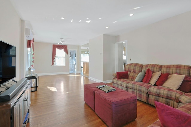 living area featuring an AC wall unit, light wood finished floors, recessed lighting, and baseboards