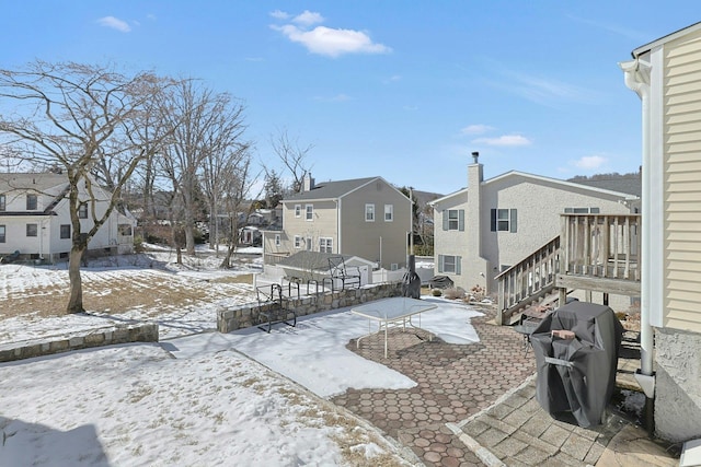 yard layered in snow with stairs and a residential view