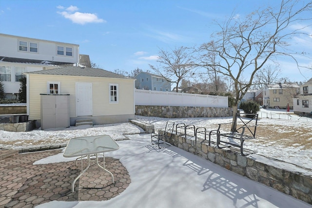 snow covered patio featuring entry steps, fence, and a residential view