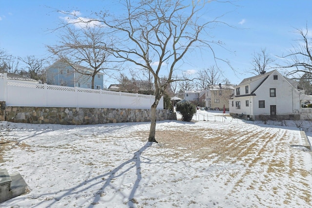 yard covered in snow featuring a residential view and fence