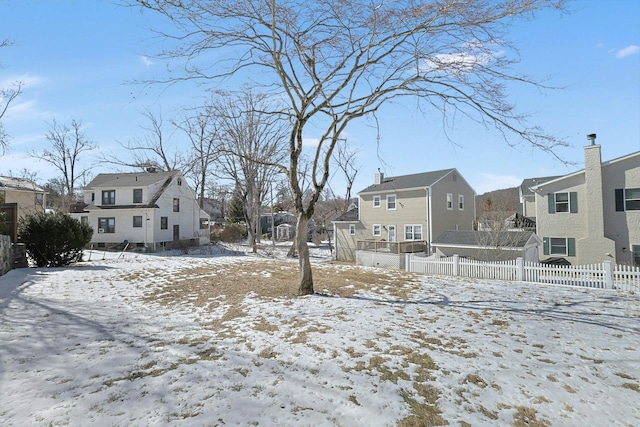 yard layered in snow featuring fence and a residential view