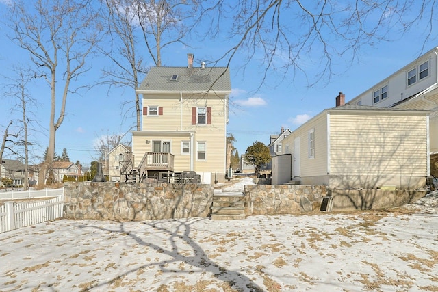 snow covered property with a chimney, a residential view, and fence