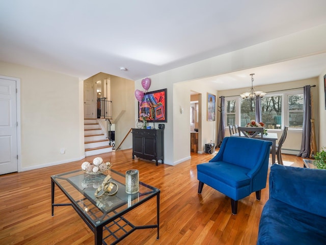 living room featuring light wood-style floors, a chandelier, stairway, and baseboards