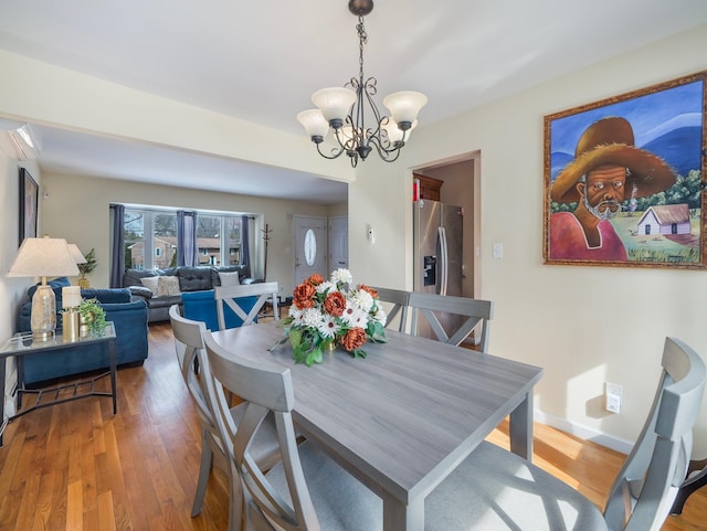 dining space featuring a chandelier, baseboards, and wood finished floors