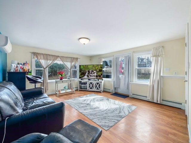 living room with a healthy amount of sunlight, a wall mounted air conditioner, light wood-style flooring, and baseboard heating