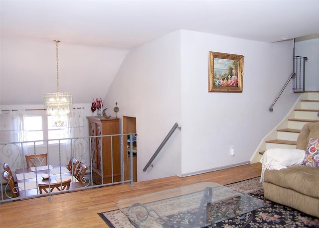 living room featuring lofted ceiling, a notable chandelier, stairway, and wood finished floors