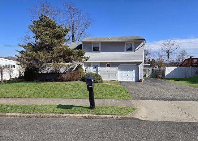 colonial-style house featuring an attached garage, driveway, a front yard, and fence