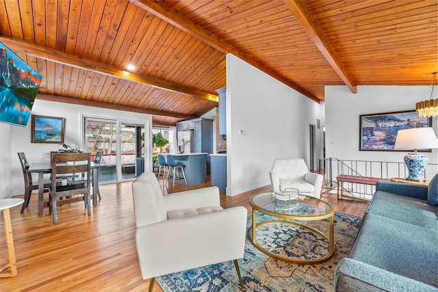 living area with lofted ceiling with beams, an inviting chandelier, light wood-type flooring, and baseboards