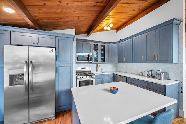 kitchen featuring backsplash, lofted ceiling with beams, appliances with stainless steel finishes, glass insert cabinets, and a sink