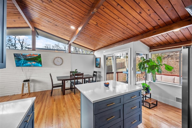 interior space featuring vaulted ceiling with beams, light countertops, light wood finished floors, and visible vents