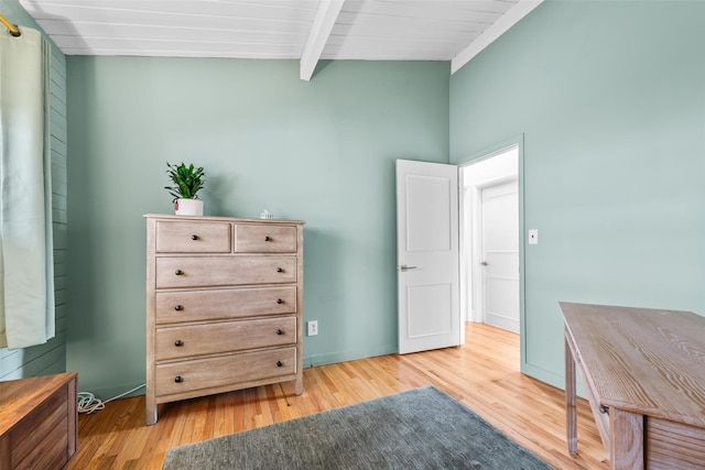 interior space with light wood-type flooring, baseboards, and beam ceiling