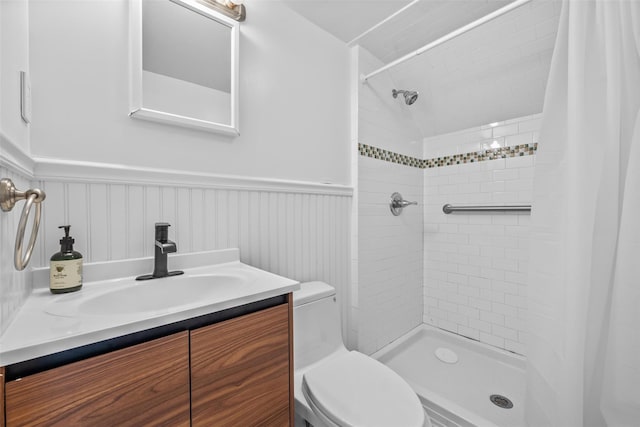 full bath featuring a stall shower, wainscoting, vanity, and toilet