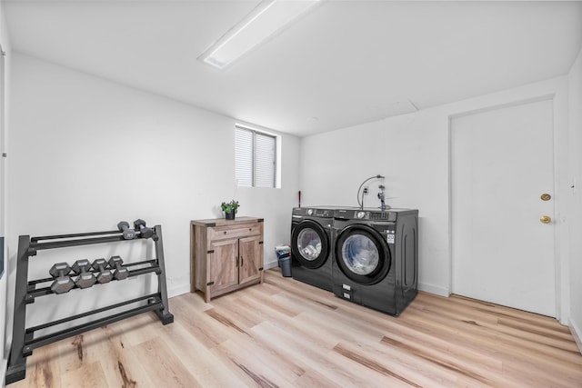 laundry area with laundry area, baseboards, washer and clothes dryer, and wood finished floors