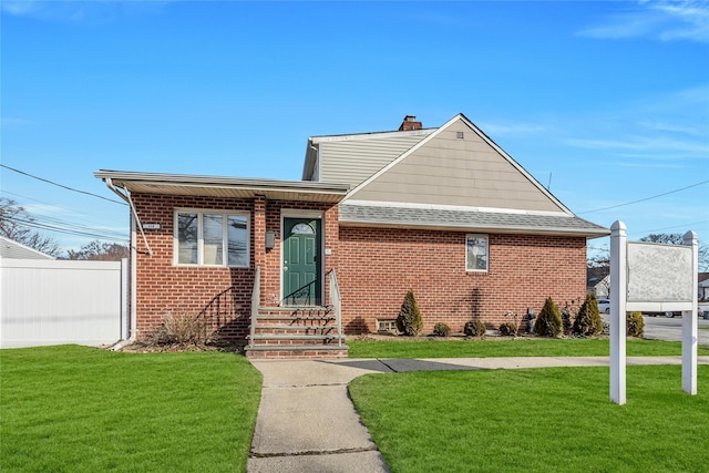 view of front facade featuring brick siding, fence, entry steps, a front yard, and roof with shingles