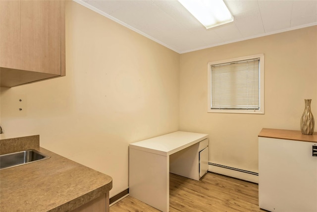 clothes washing area featuring a sink, a baseboard heating unit, light wood-style flooring, and crown molding