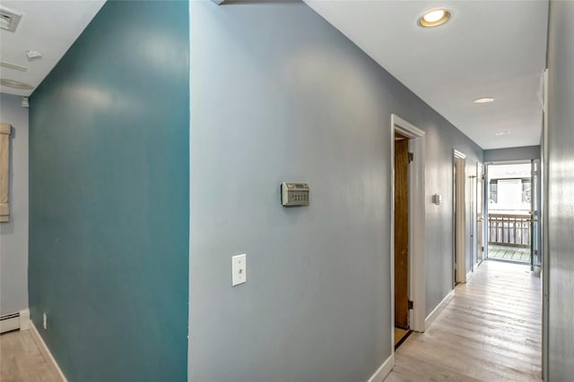 hallway with light wood-type flooring, baseboards, and visible vents