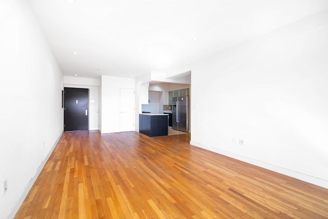 unfurnished living room with baseboards and wood finished floors