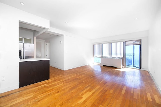 unfurnished living room featuring light wood finished floors, recessed lighting, and baseboards