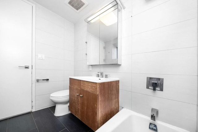 bathroom with toilet, a washtub, vanity, visible vents, and tile walls