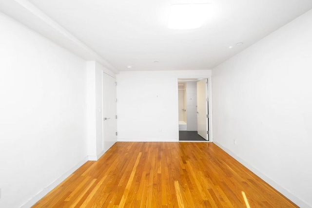 spare room featuring light wood-type flooring and baseboards