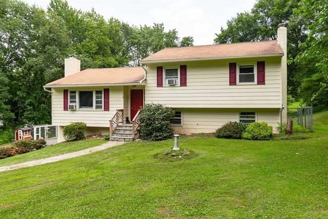 split level home featuring a chimney and a front yard