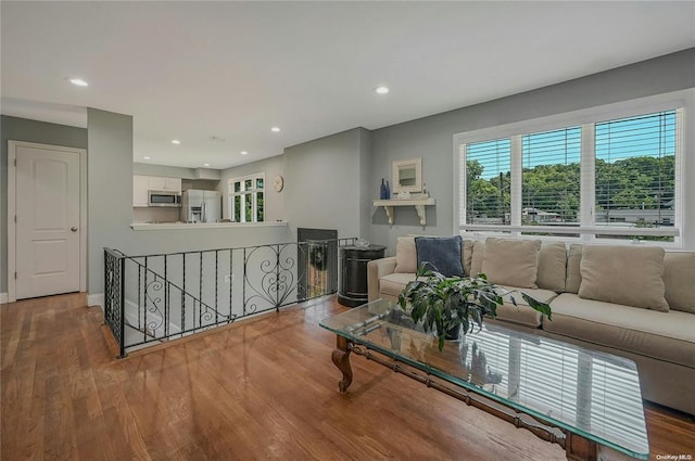 living area with baseboards, wood finished floors, and recessed lighting