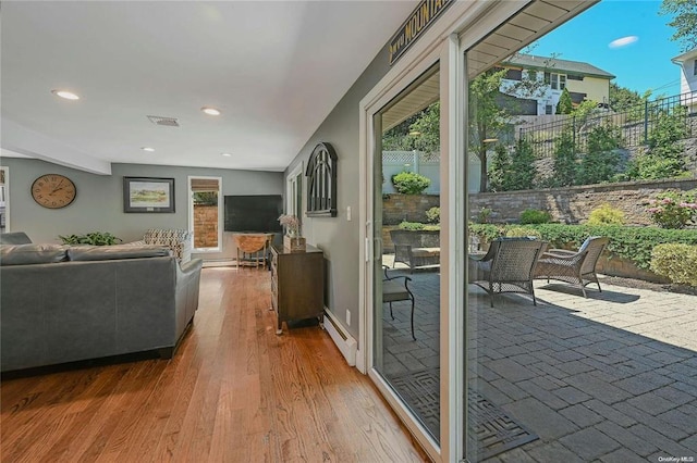 interior space with visible vents, a baseboard heating unit, wood finished floors, and recessed lighting