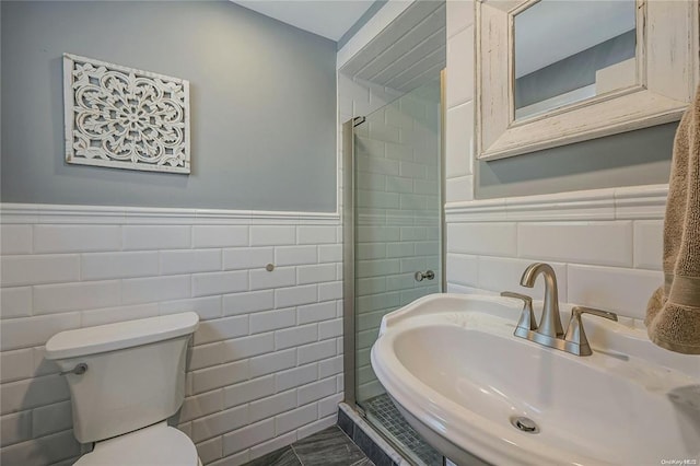 bathroom featuring a wainscoted wall, a shower stall, tile walls, and a sink