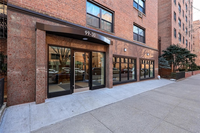 view of exterior entry with brick siding and fence