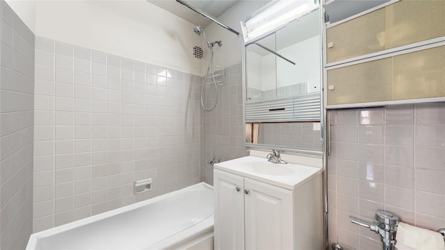 full bath with shower / washtub combination, vanity, and tile walls