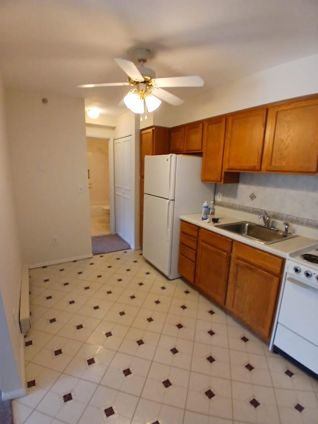 kitchen with brown cabinetry, electric stove, freestanding refrigerator, light countertops, and a sink