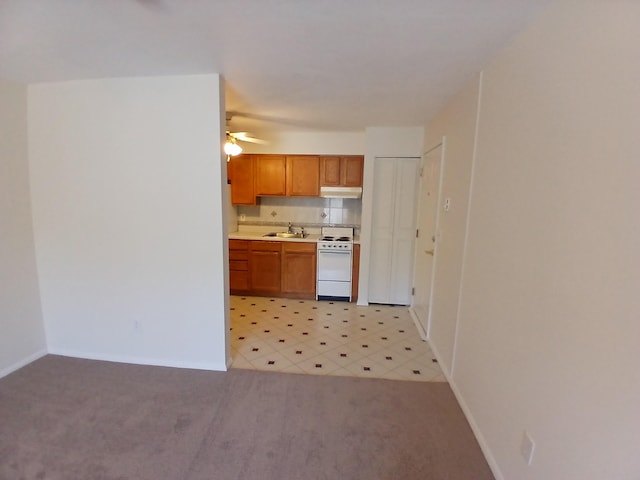 kitchen featuring brown cabinets, light countertops, white electric range, light colored carpet, and under cabinet range hood