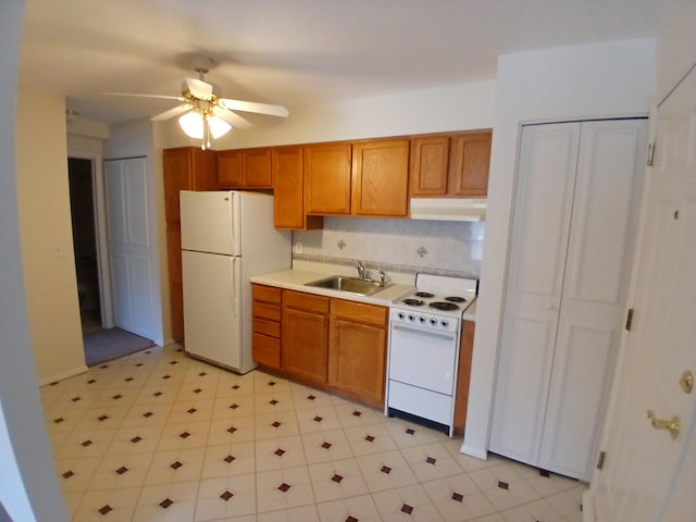 kitchen with under cabinet range hood, white appliances, a sink, light countertops, and brown cabinetry