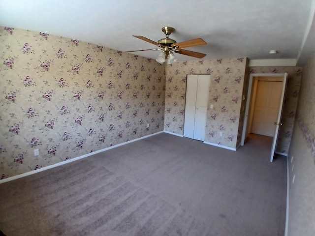 unfurnished room featuring wallpapered walls, dark carpet, a ceiling fan, and baseboards