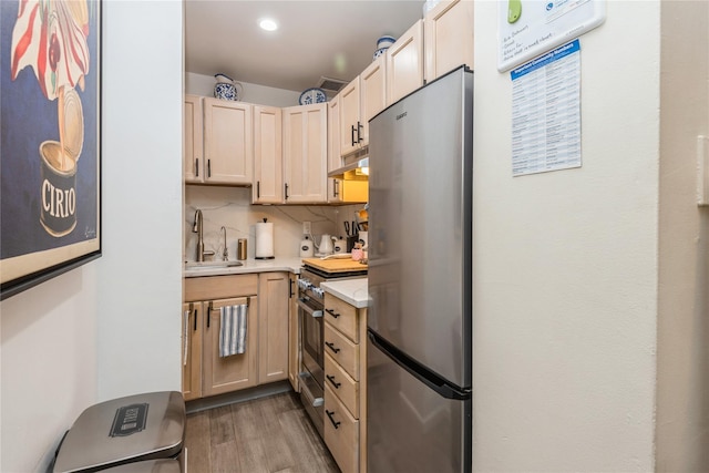 kitchen with dark wood finished floors, light countertops, light brown cabinetry, appliances with stainless steel finishes, and a sink